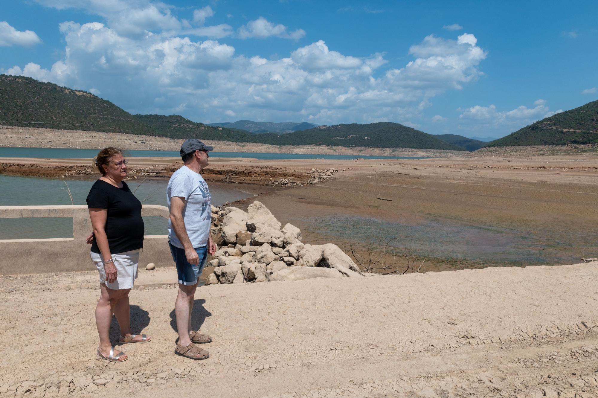 Dos vecinos aprovechan el bajo nivel del agua en el embalse de Rialb (Lleida) para ver el antiguo pueblo de Tiurana.