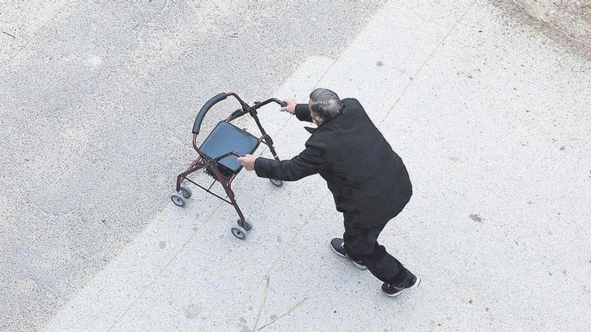 Una persona mayor camina con ayuda de un andador, sola, en las calles de Zaragoza.