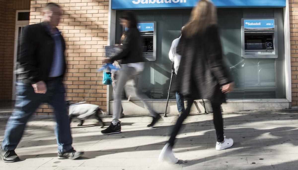 Varios clientes utilizan los cajeros de una entidad en Alicante.