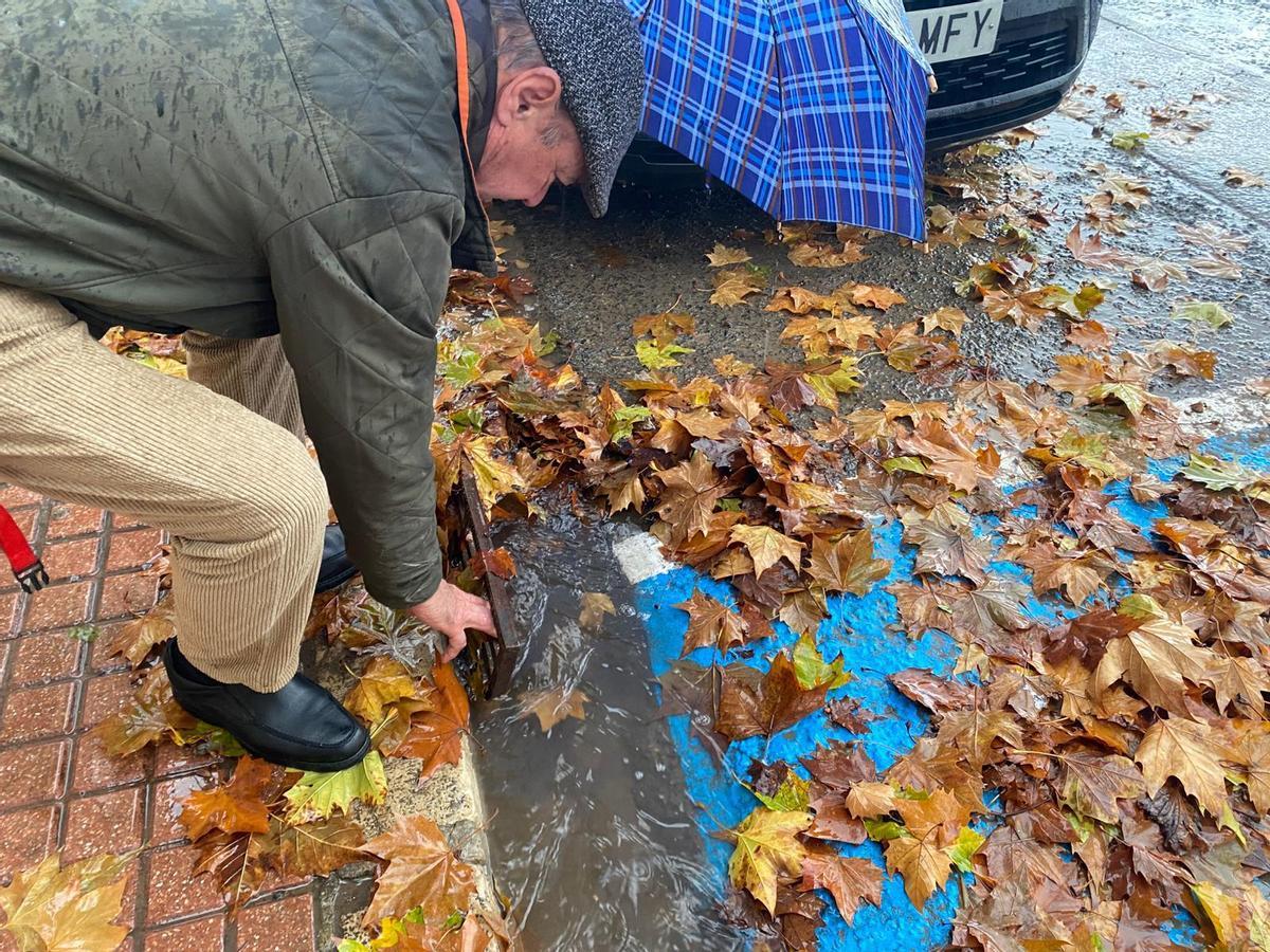 Un vecino del Parque Alcosa retira hojas del alcantarillado.