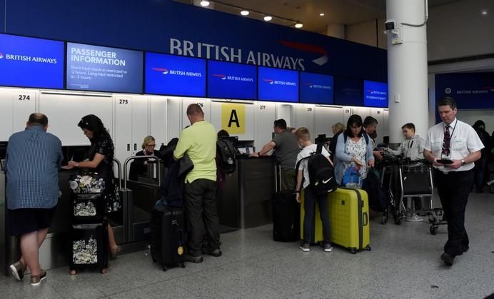 People wait with their luggage at the British ...