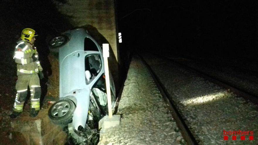 El cotxe caigut a tocar de la via del tren.