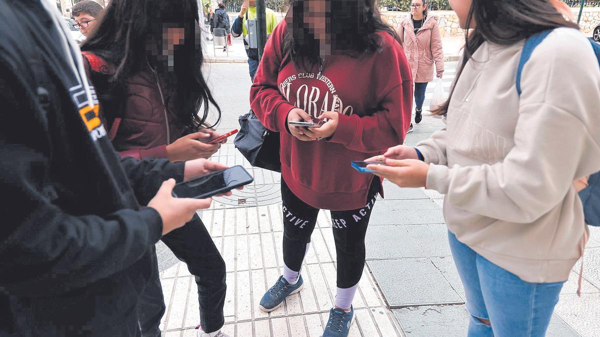 Alumnas  de un instituto utilizan el móvil tras salir de clase.