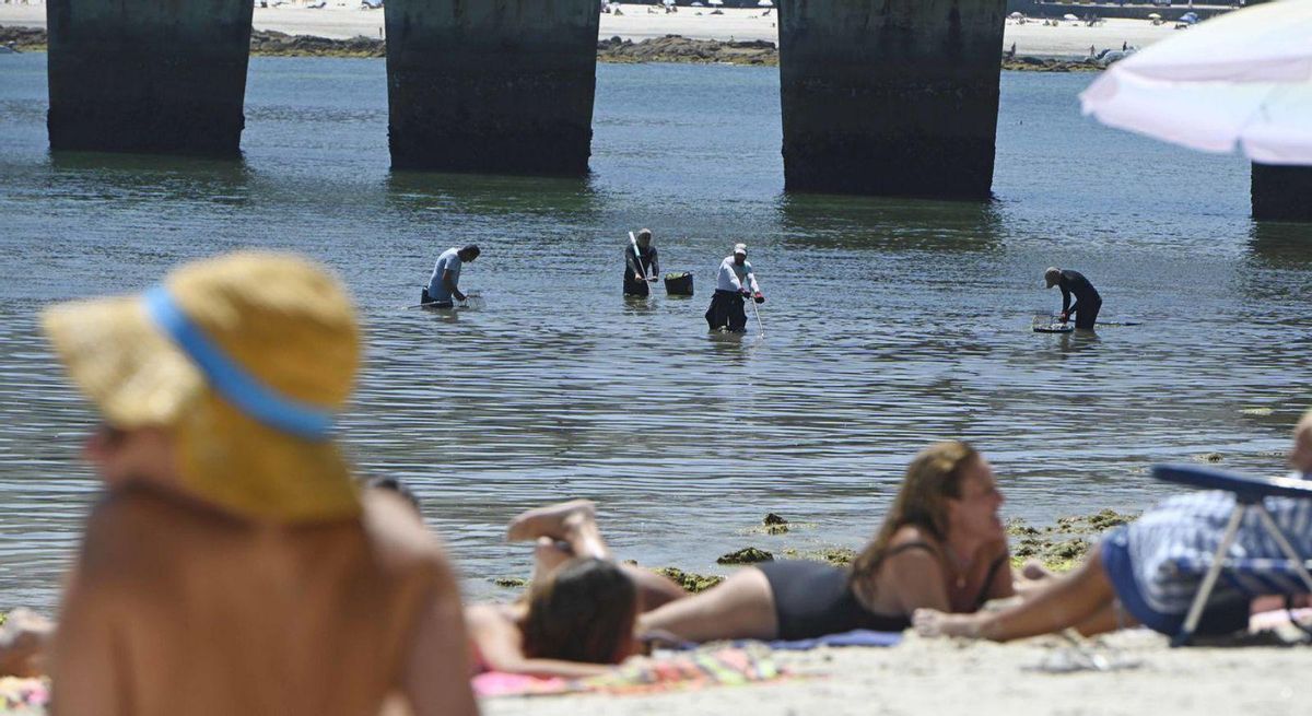 Varios profesionales faenando en el mar, mientras los veraneantes descansan. | P. H. Gamarra