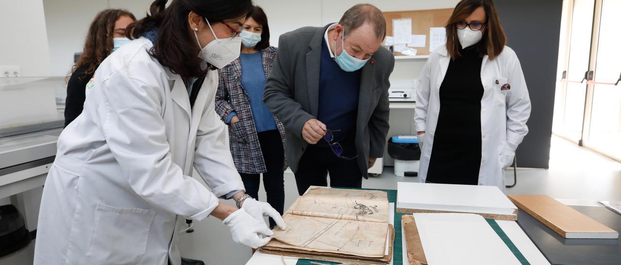 María José Velasco muestra un antiguo documento portuario a Santiago Rodríguez Vega en un aula del área de Restauración y Conservación de bienes culturales.