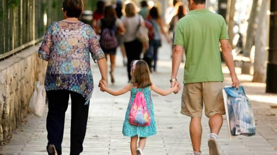 Una niña acude a un colegio de Valencia cogida de la mano de sus familiares.