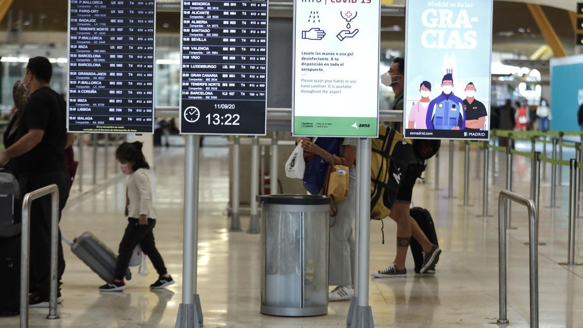 Pasajeros cerca de páneles informativos en la terminal T4 del aeropuerto Adolfo Suárez Madrid-Barajas.