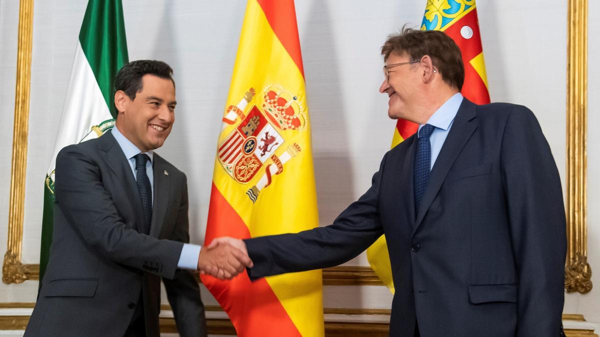 El presidente de la Junta de Andalucía, Juanma Moreno, y el de la Generalitat Valenciana, Ximo Puig, se saludan al comienzo de su primera reunión.