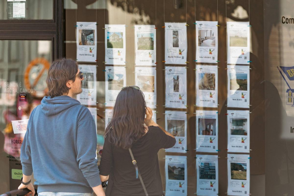 Una pareja ante el escaparate de una inmobiliaria en Santiago de Compostela.