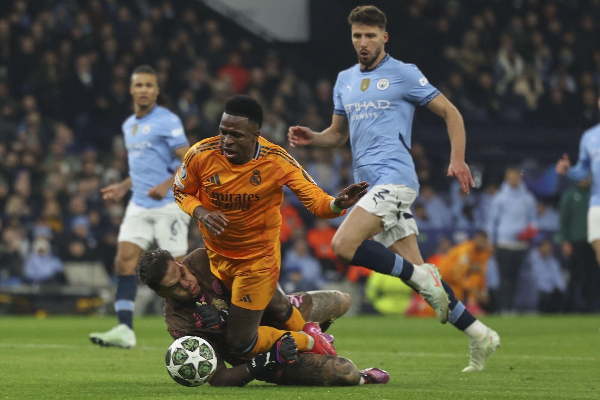 Manchester City's goalkeeper Ederson collides with Real Madrid's Vinicius Junior during the Champions League playoff first leg soccer match between Manchester City and Real Madrid at the Etihad Stadium in Manchester, England, Tuesday, Feb. 11, 2025. (AP Photo/Darren Staples)