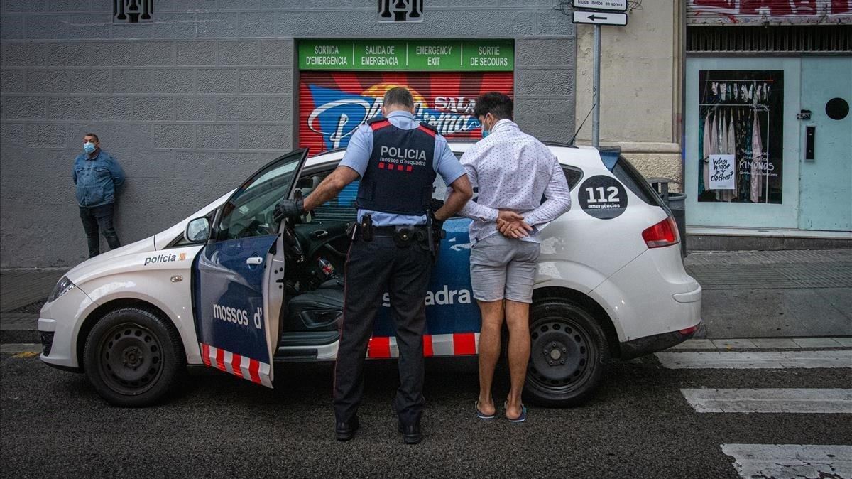 Un agente de los Mossos lleva al coche patrulla a uno de los detenidos.