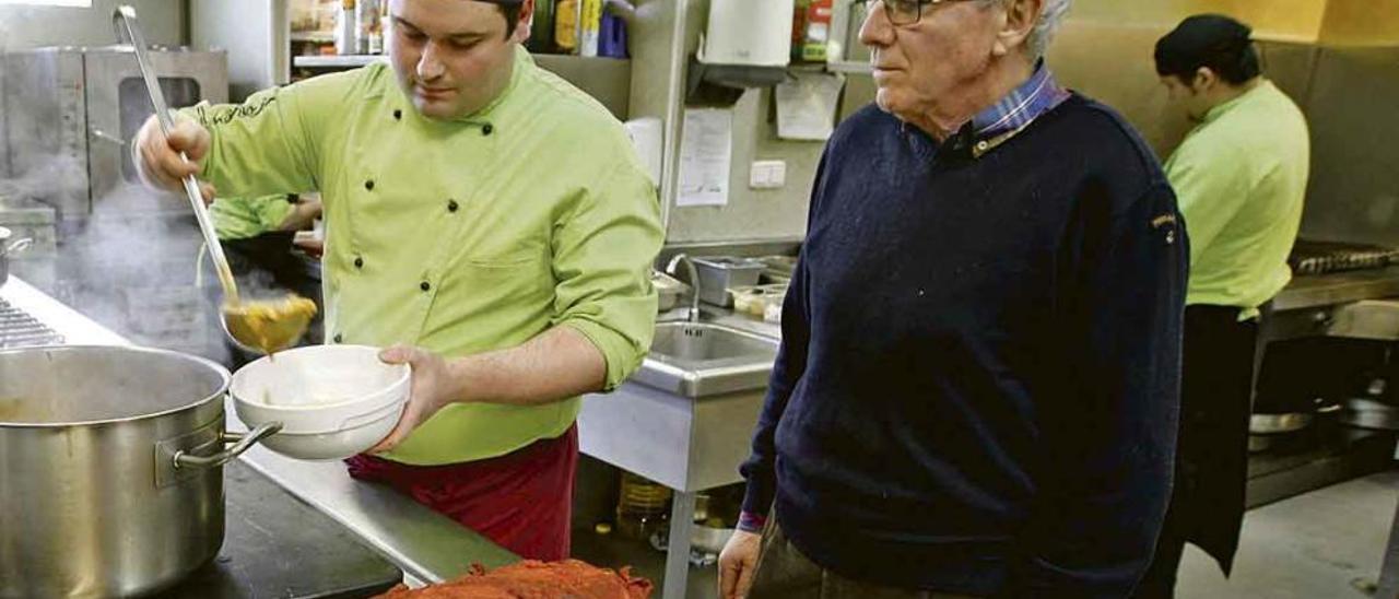 José Silverio Álvarez, a la derecha, observa la elaboración y servicio de un menú en la cocina del restaurante que regenta en Latores.