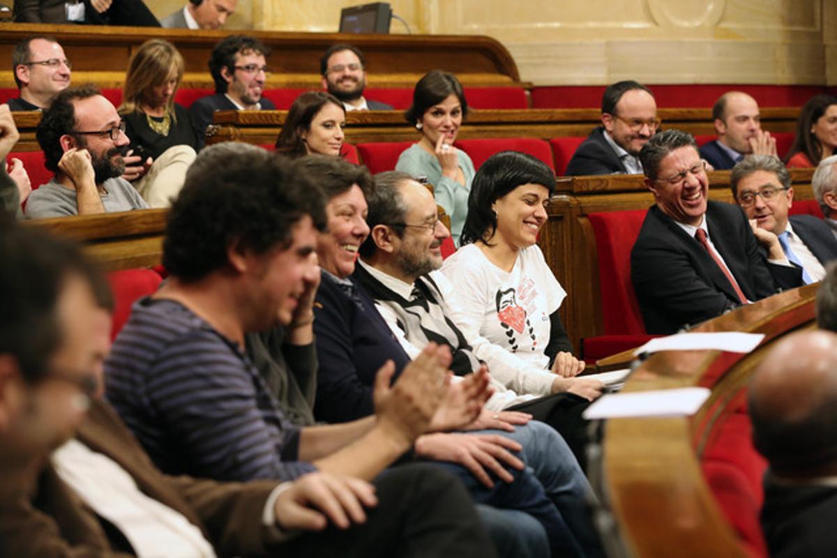 Diputados de la CUP y del PP rien tras una broma en el debate de investidura del nuevo President de la Generalitat, Carles Puigdemont