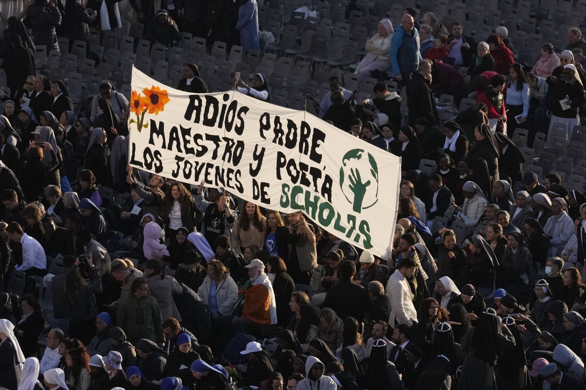 A banner with writing reading in Spanish "Farewell Father, teacher and poet", is seen in the crowd arriving for the funeral of Pope Francis in St. Peter's Square at the Vatican, Saturday, April 26, 2025. (AP Photo/Gregorio Borgia)