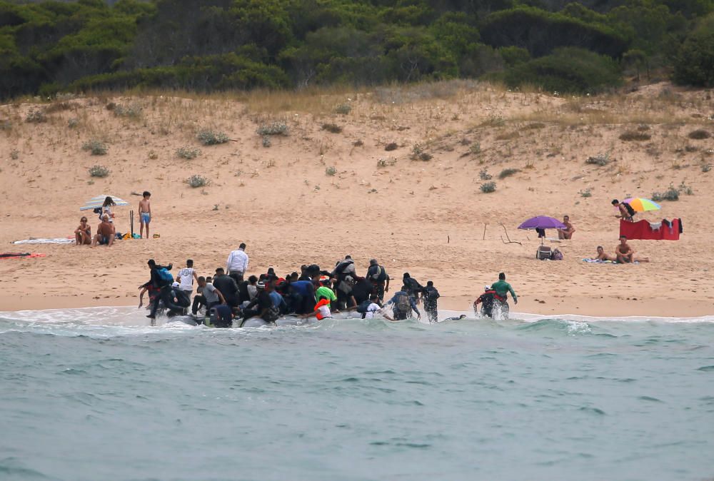 Una patera llega a una playa de Cádiz ante la mirada de los bañistas