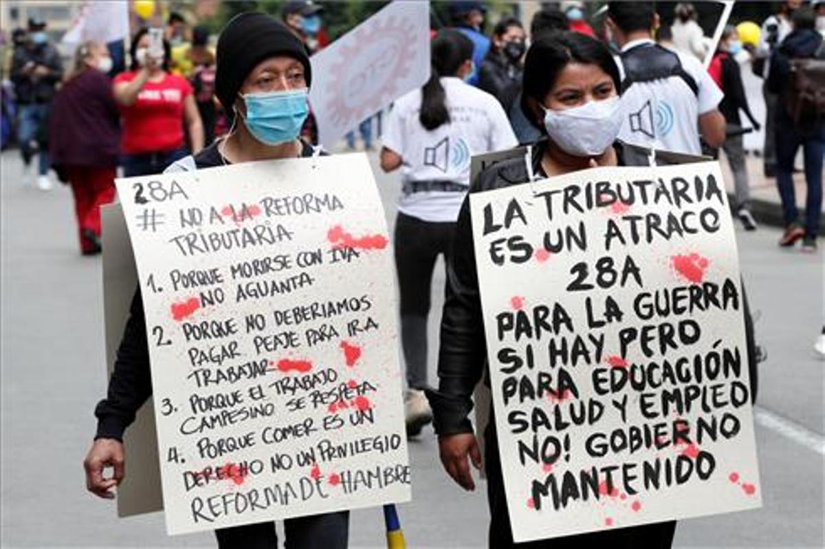 Dos mujeres portan carteles de protesta durante la jornada de manifestaciones.