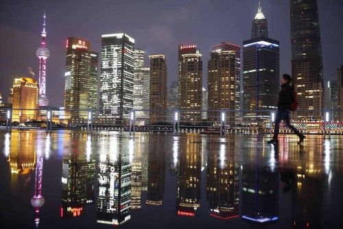 Una mujer camina frente al distrito financiero de Pudong en Shangai