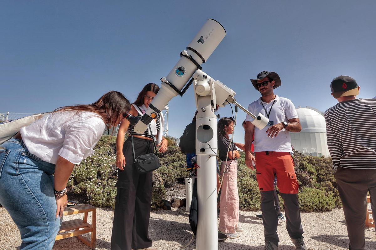 Una joven mira al Sol por el telescopio en las jornadas abiertas del Observatorio del Teide para conocer el corazón de la astrofísica canaria.