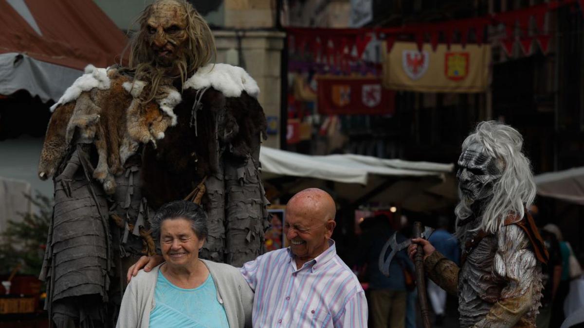 Sobre estas líneas, el director de la Banda de Música, Xuacu Llaneza, a la batuta. En las imágenes inferiores,  ambiente en el mercado medieval y público en  el mercado de  ganados durante el arrastre  de bueyes. |