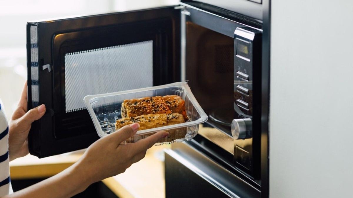 Envase de plástico con comida a punto de ser introducido en el microondas