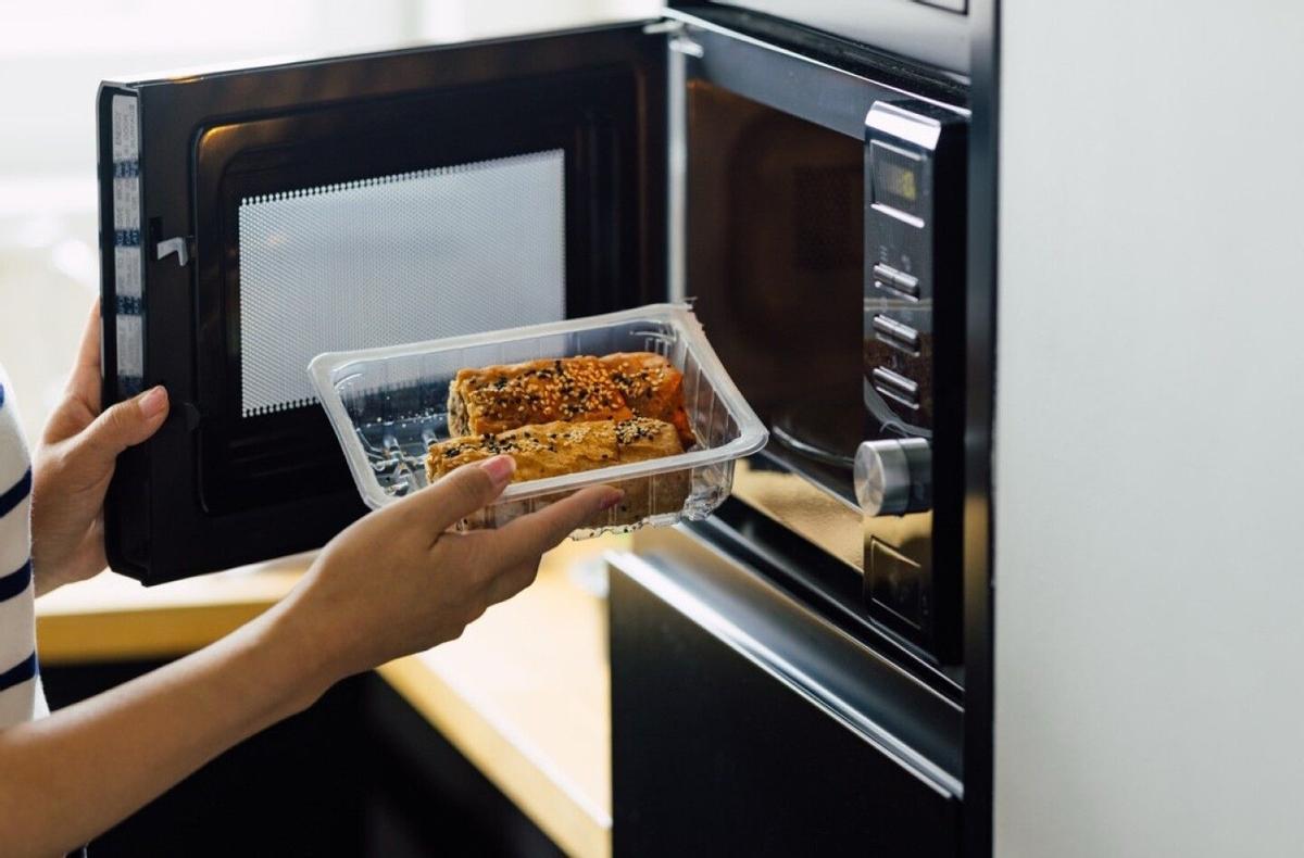Envase de plástico con comida a punto de ser introducido en el microondas