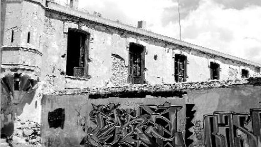 Muro exterior lleno de grafitis, y fachada con grietas y desconchados de la Casa de Camp.