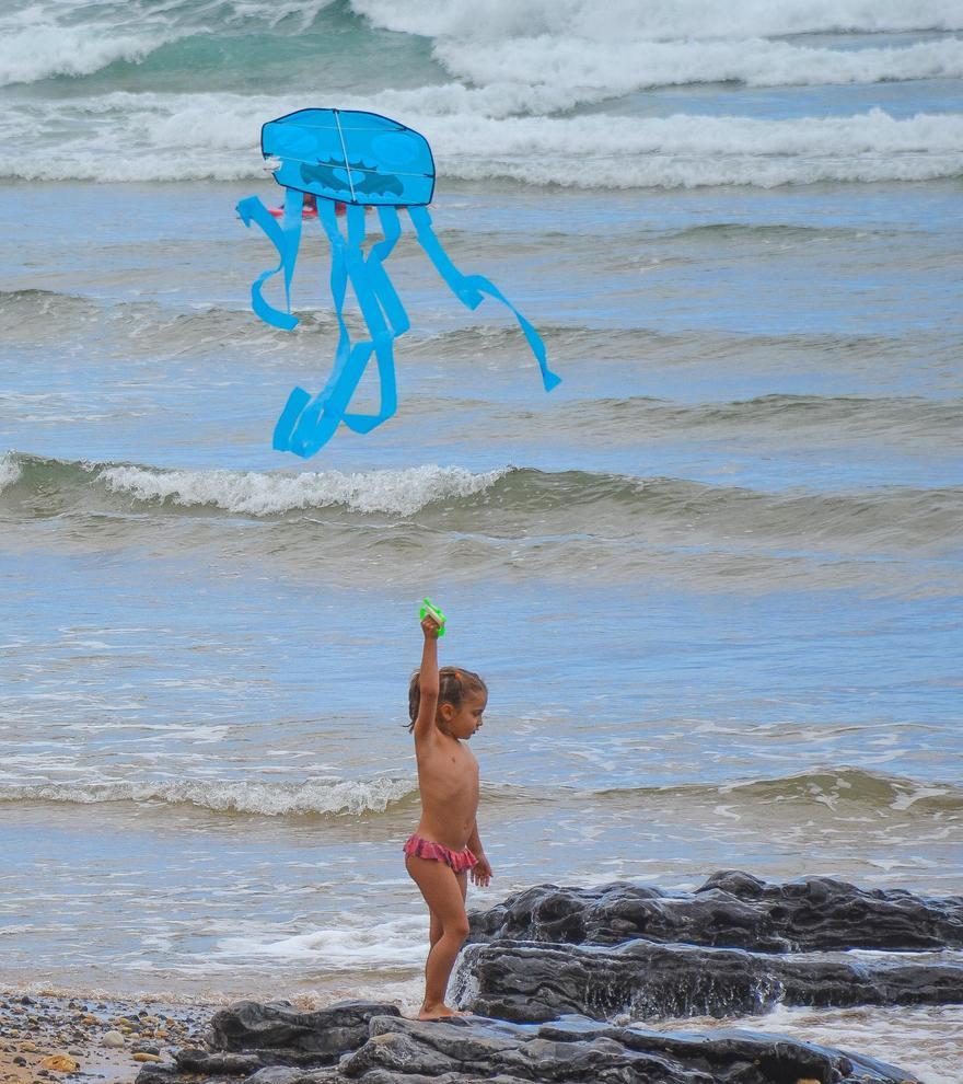 La niña Lucía Santos Martín hace volar su cometa en forma de medusa, en la playa de La Espasa. | Ana Paz Paredes