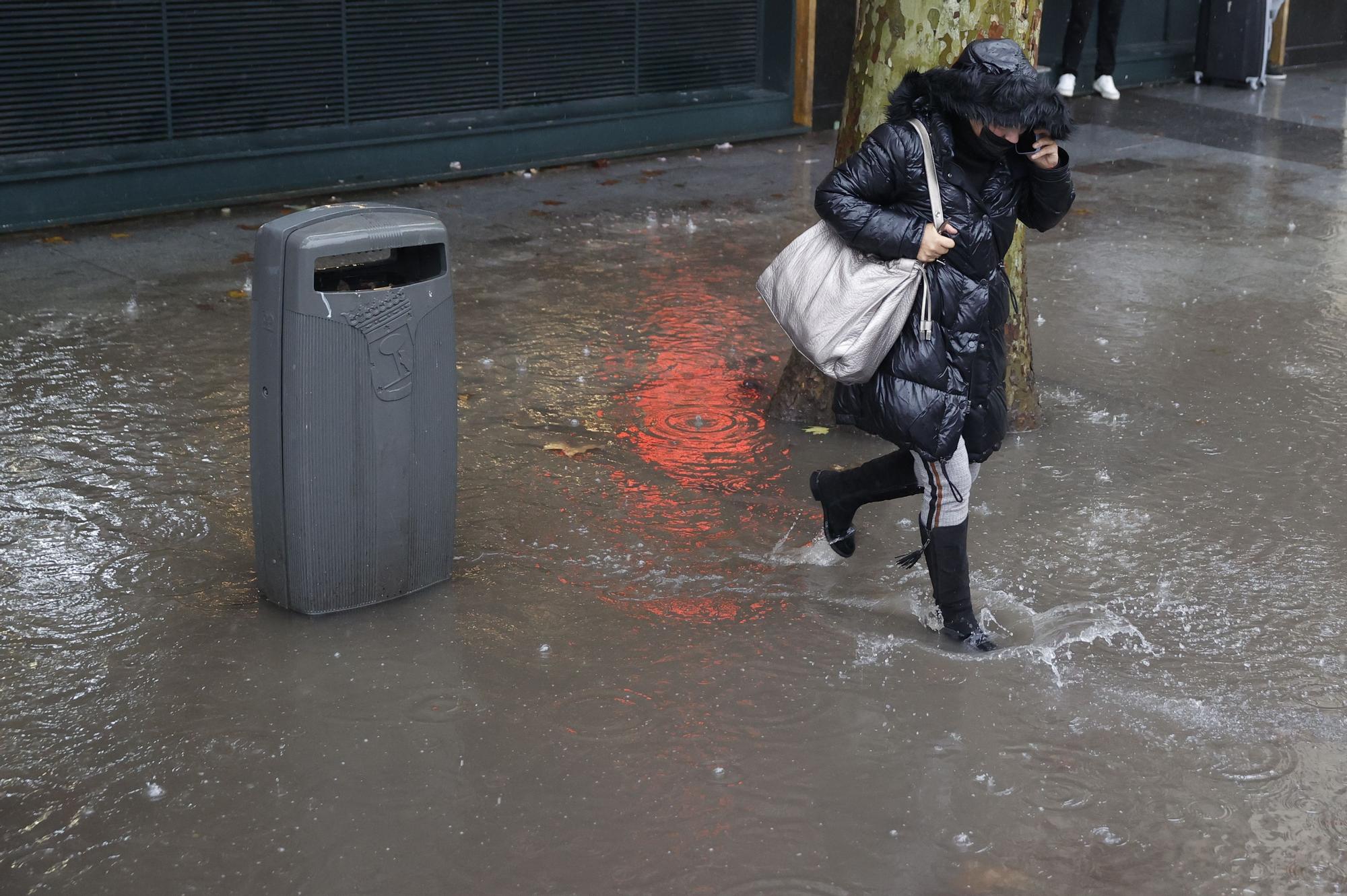 Una mujer corre para protegerse de la lluvia que se registra este martes en Madrid.