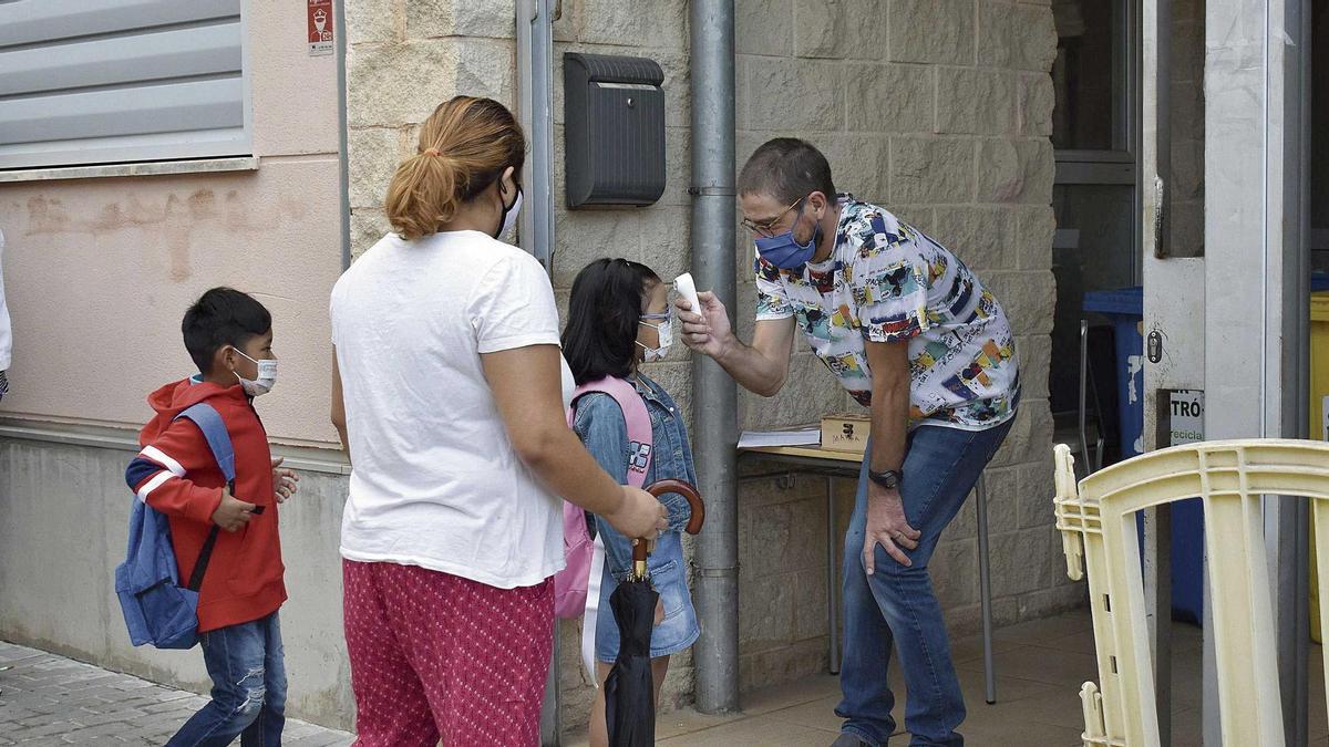 Un maestro del CEIP Es  Fossaret toma la  temperatura a los  niños al llegar.