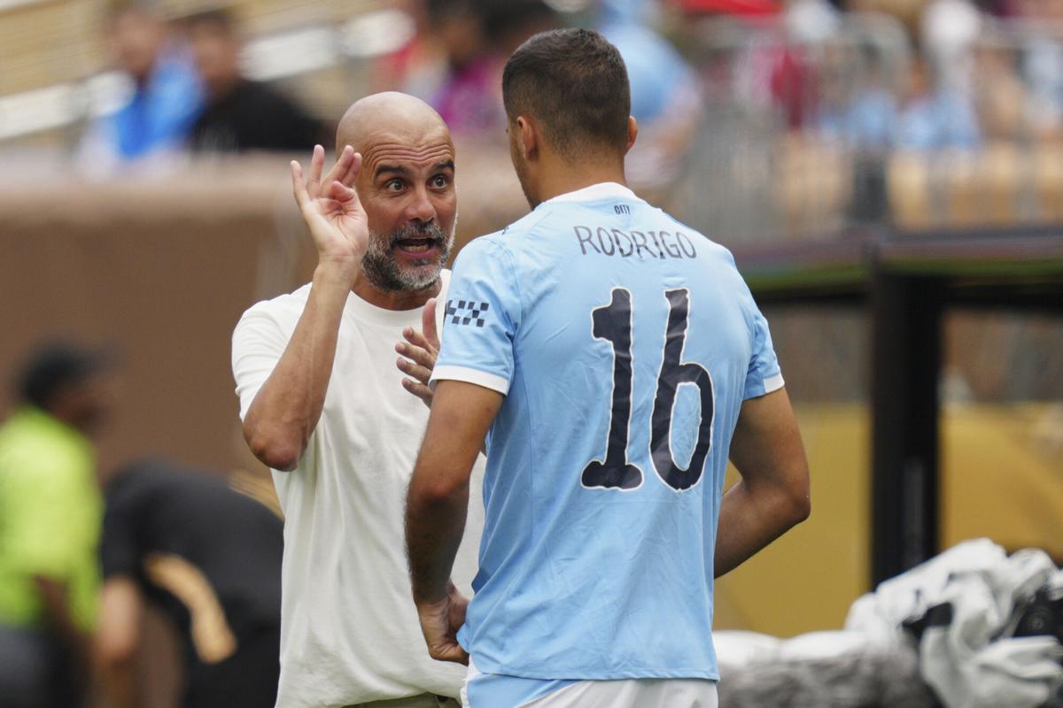 Guardiola conversa con Rodrigo en un partido del Manchester City.