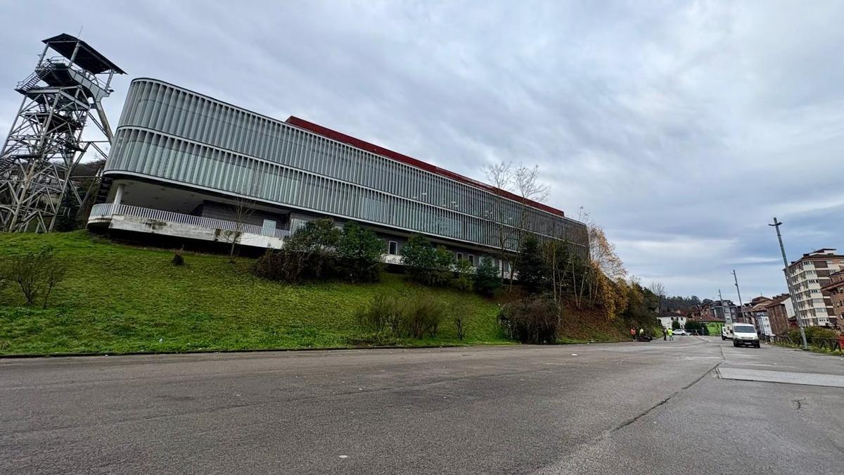 El aparcamiento del centro TIC de El Entrego, a la izquierda, vacío para el inicio de las obras de construcción del nuevo edificio
