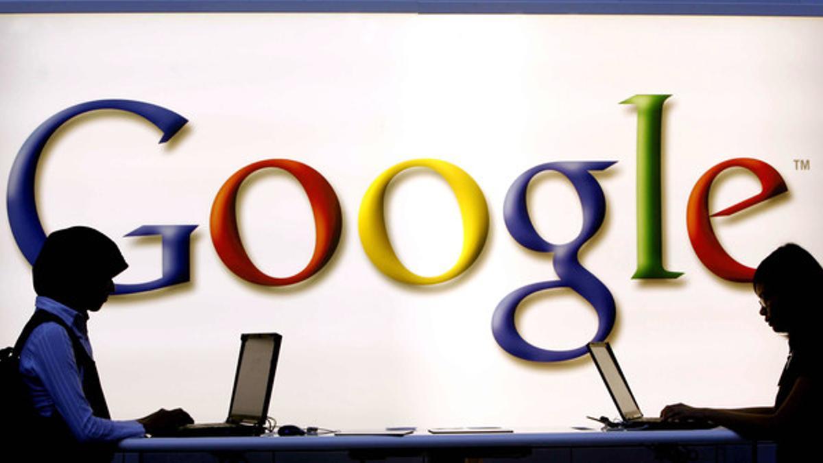 Dos internautas navegan por la red junto a un letrero de Google, en Fráncfort.