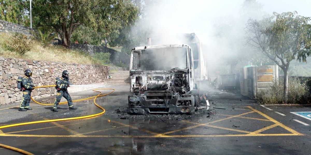 Los bomberos sofocan el incendio en el camión de la basura.