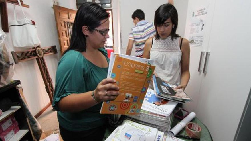 Dos voluntarias ordenan el material escolar donado en la sede de la hermandad.