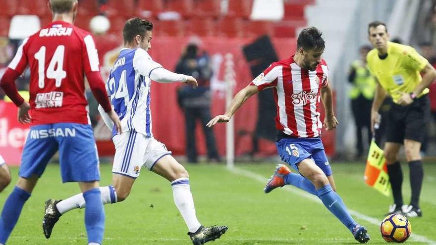 Canella despeja un balón presionado por David Concha, con Burgui a la izquierda.