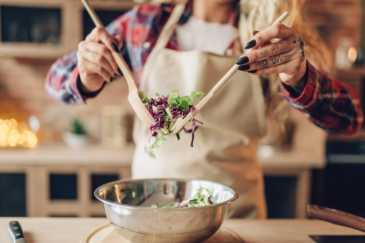 Female cook in apron prepares fresh salad