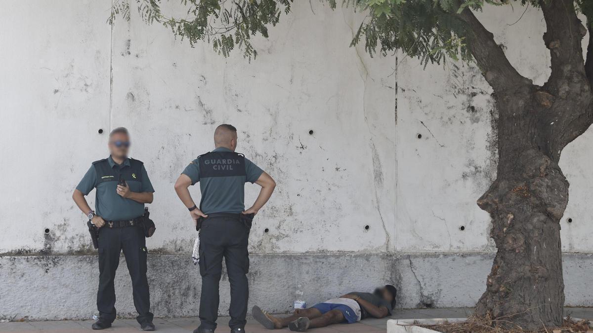 Dos agentes de la Guardia Civil observan a una persona tumbada, a 1 de agosto de 2026, en Ceuta (España).
