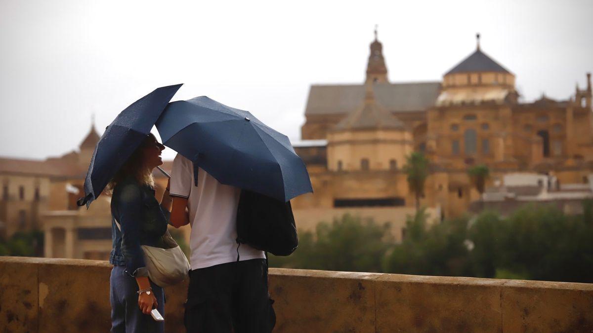 Una pareja en el entorno del Puente Romano, con paraguas en una jornada lluviosa como la de este martes en Córdoba.