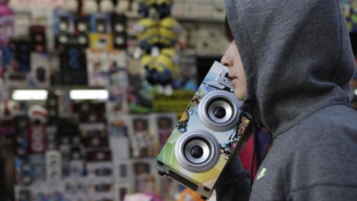 Un joven con un altavoz autoamplificado y con conexión bluetooth, en una tómbola en el barrio de Sant Antoni.