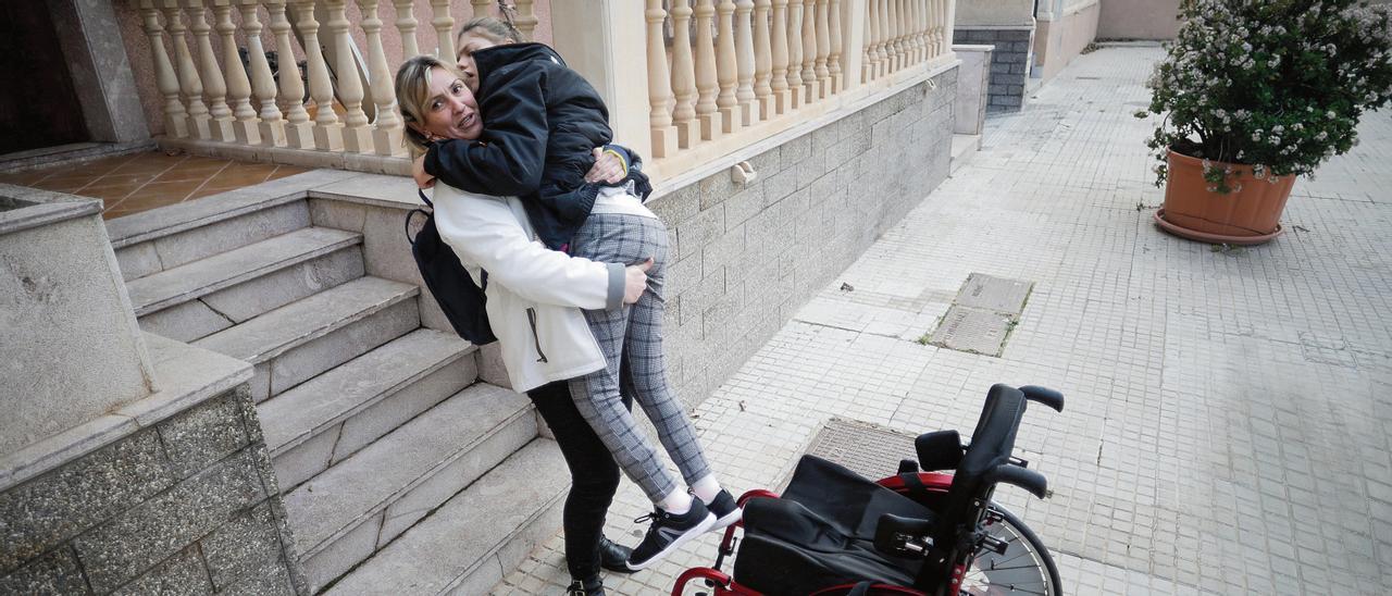 Teresa lleva en brazos a su hija, Alba, para superar las escaleras.