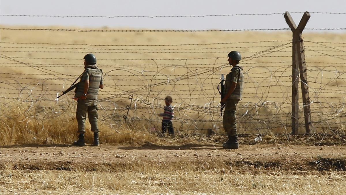 Un niño sirio espera tras las vallas de la frontera para cruzar hacia Turquía cerca de Akcacale (sureste), en el 2015