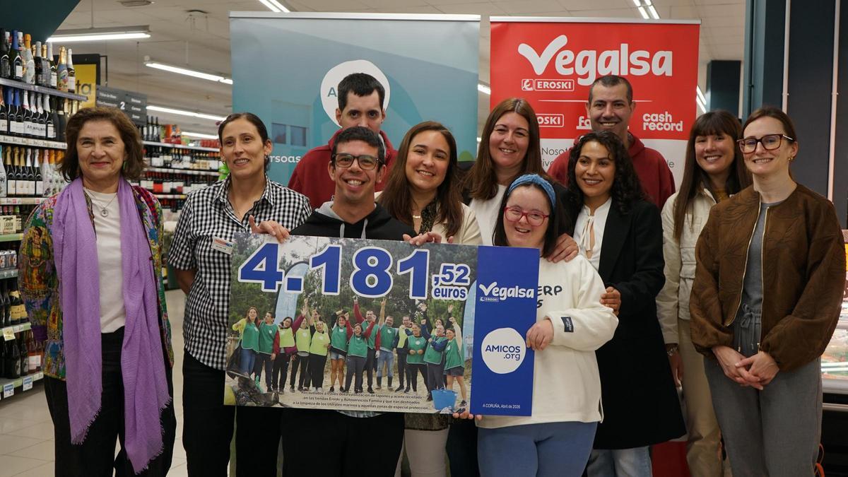 Usuarios y directivos de Amicos y Vegalsa-Eroski mostrando el cheque solidario.