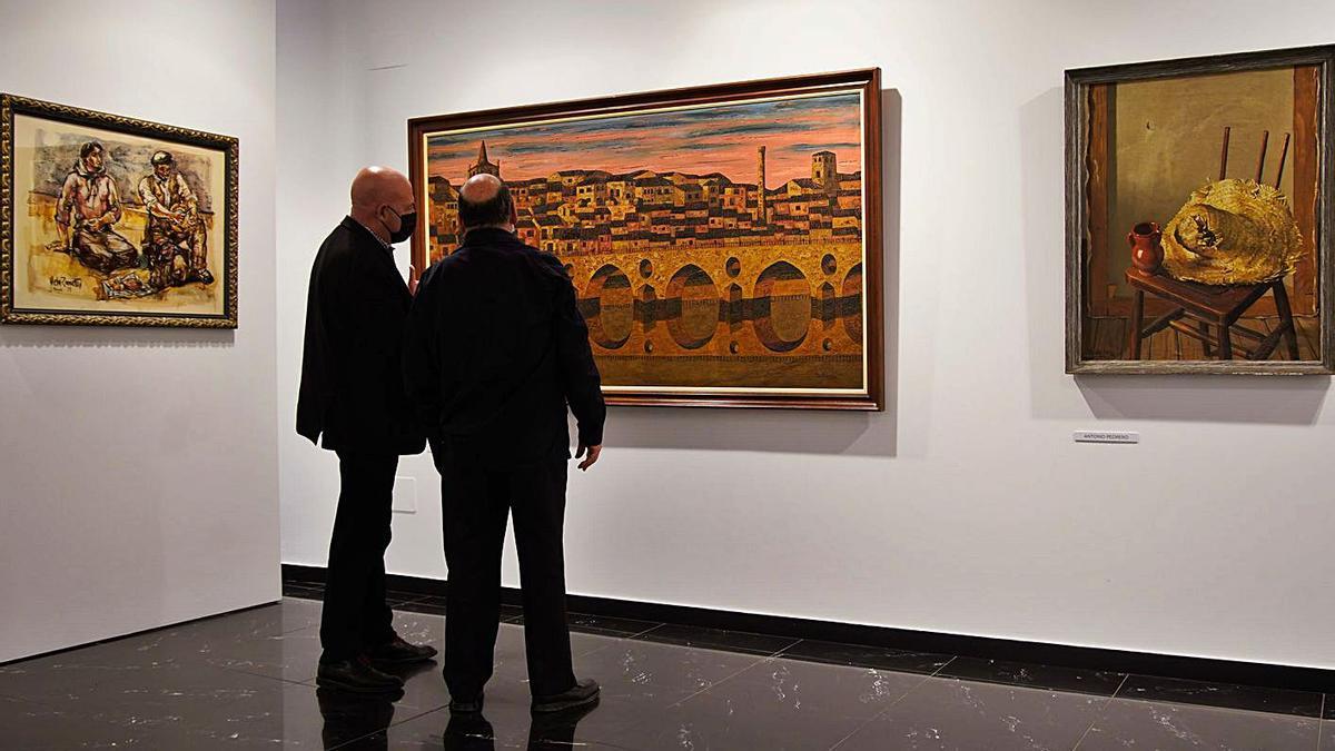 Ángel Almeida (izquierda), junto a un visitante, observan el cuadro de Alfonso Bartolomé.