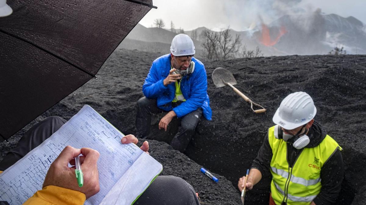 Tres científicos realizan mediciones, con excavaciones en la ceniza acumulada durante los 71 días del proceso eruptivo.