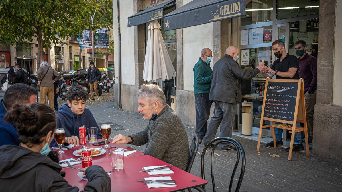 Barcelona 02/12/21 Sociedad. Entrada en vigor del pasaporte covid en bares y restaurantes. Bar Gelida. Eixample esquerre. Se ha instalado una pancarta de advertencia para frenar la entrada sin control de clientes. Mientras dentro se requiere pasaporte covid para comer, fuera en la terraza no. AUTOR: MANU MITRU