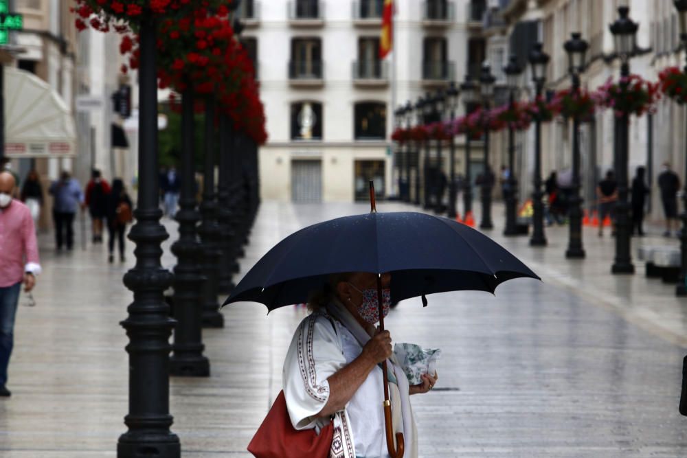 Imágenes de una lluviosa mañana de jueves en el centro de Málaga, donde al paisaje ya habitual de pocas personas y la mayoría de ellas con guantes y mascarillas se le han añadido los preparativos de bares, cafeterías y terrazas que se preparan para el inminente cambio de fase de la desescalada de la ciudad.