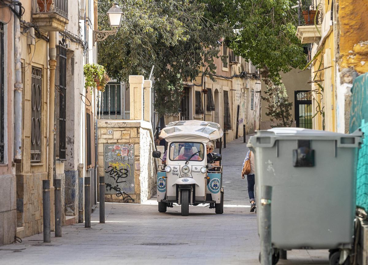 Un grupo de cuatro turistas a bordo de un tuk tuk durante una visita guiada al Casco Antiguo de Alicante.