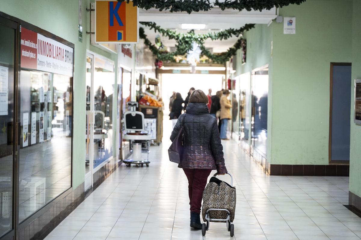 Una vecina con su carro de la compra junto al único local inactivo.