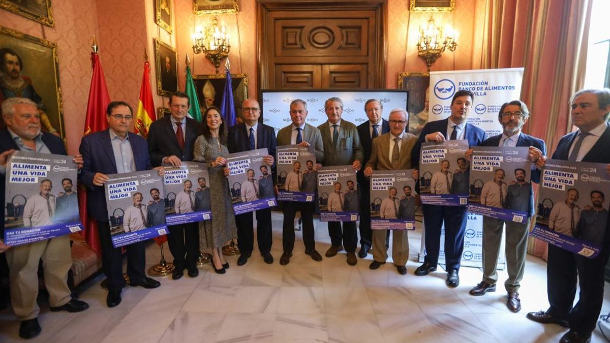 Patronos y voluntarios del Banco de Alimentos de Sevilla en la presentación de la gran recogida de primavera en el Ayuntamiento, junto al alcalde y miembros del equipo de gobierno municipal.