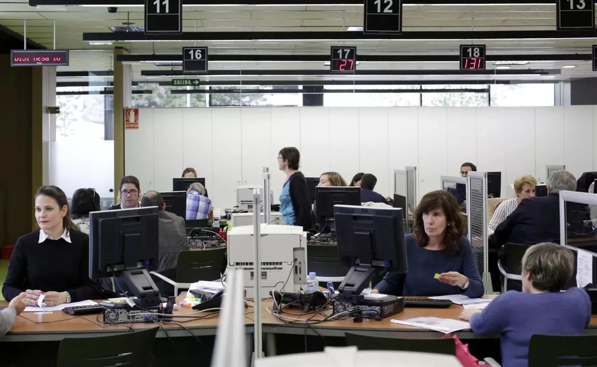 Empleados públicos atienden a los ciudadanos en una oficina.